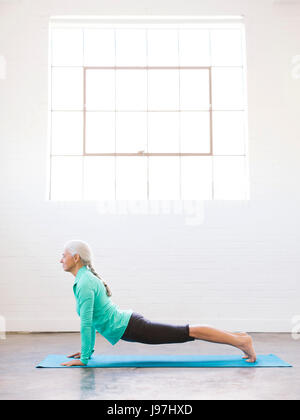 Senior donna pratica lo yoga del tappetino Foto Stock
