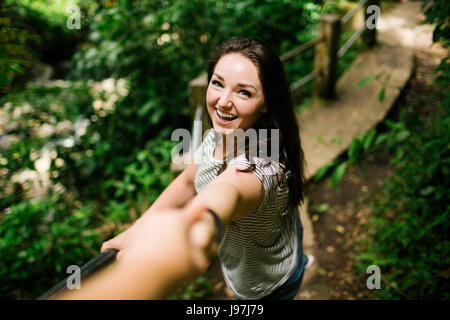 Isole dei Caraibi, Saint Lucia, sorridente donna in piedi sul percorso, holding della persona e la mano guardando la fotocamera Foto Stock