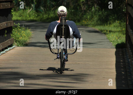 Uomo in sella a una due ruote Recumbent bicicletta in posizione di parcheggio Foto Stock