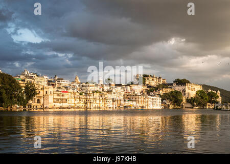 Tramonto sul lago Pichola di Udaipur città vecchia di fronte al lago e il palazzo della città nel Rajasthan, India Foto Stock