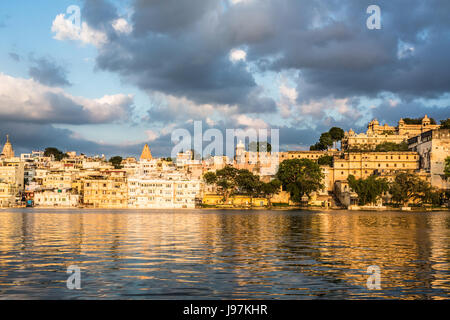 Tramonto sul lago Pichola di Udaipur città vecchia di fronte al lago e il palazzo della città nel Rajasthan, India Foto Stock