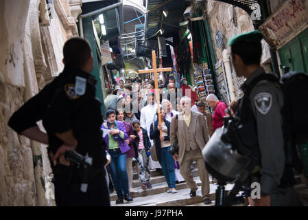 Soldati israeliani e la polizia guarda come Palestinesi cristiani portare una croce dal Redentore chiesa luterana nella Città Vecchia di Gerusalemme al Giardino del Getsemani sul Monte degli Ulivi durante un Giovedì Santo Processione, 17 aprile 2014. La comunità internazionale non ha riconosciuto Israele l'annessione della parte orientale di Gerusalemme, compresa la città vecchia, e continua a essere considerato territorio palestinese occupato ai sensi del diritto internazionale. Foto Stock