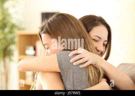 Le fanciulle felici abbracciando a casa seduto su un divano nel salotto di casa Foto Stock