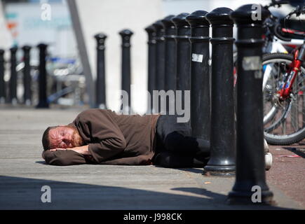 Un senzatetto uomo dorme sul terreno al di fuori lo stadio nazionale del Galles (aka Principato Stadium) Foto Stock