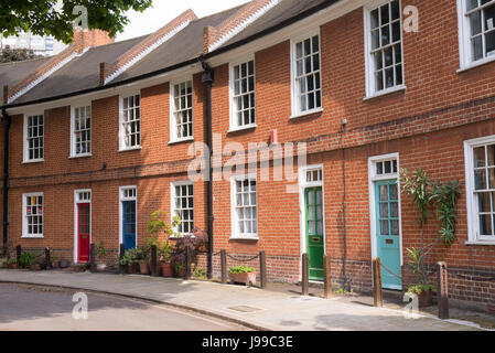 Classic British crescent con vittoriano ristrutturato in mattoni rossi con case variopinte porte su una strada locale in Londra, Regno Unito Foto Stock