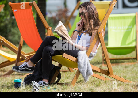 Festival di fieno, Hay on Wye, Wales, Regno Unito. Dal 01 Giugno, 2017. Regno Unito Meteo: una giovane donna di relax con un libro seduto in una sedia a sdraio, godendo la multa caldo e soleggiato su 1 giugno, il primo giorno di estate meteorologica al 2017 Hay Festival, nella piccola cittadina gallese di Hay on Wye in rurale Powys. Oggi festeggia il suo trentesimo anno il festival della letteratura richiama alcuni dei migliori scrittori, docenti universitari e commentatori di tutto il mondo e decine di migliaia di visitatori al giorno a ciò che è stato descritto da ex presidente degli Stati Uniti Bill Clinton come 'Il Woodstock della mente'l Foto Stock