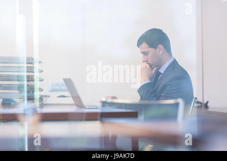 Elegante imprenditore analizzando i dati in ufficio moderno. Foto Stock