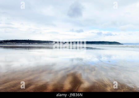 Condino, Devon, Inghilterra, Regno Unito, con la bassa marea, il cielo si riflette in un sottile strato di acqua sulla deserta spiaggia sabbiosa Foto Stock