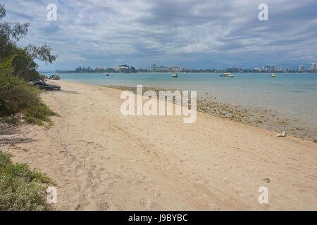 Spiaggia a riva dell'isolotto Canard e la fascia costiera di Anse Vata e la città di Noumea in background, Grande Terre isola, Nuova Caledonia, Oceania Foto Stock