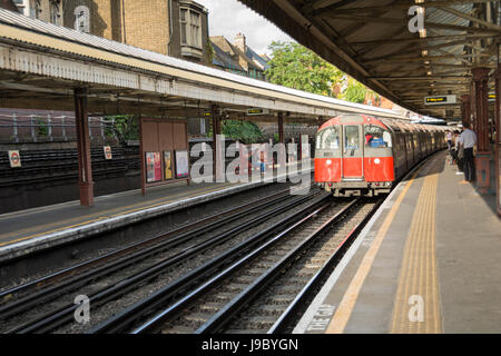 La linea Piccadilly treno tirando in Barons Court stazione della metropolitana di Piccadilly e District Line, London, Regno Unito Foto Stock