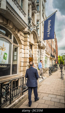 Un uomo d'affari che cammina lungo New Bond Street di fronte a Sotheby's, Mayfair, Londra, Inghilterra Regno Unito Foto Stock