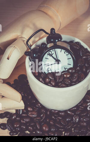 Sveglia sulla tazza di caffè ,tazza da caffè piena di chicchi di caffè con sulla scrivania in legno Foto Stock