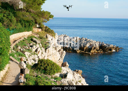 Uomo che vola un veicolo aereo senza equipaggio (drone). Saint-Jean-Cap-Ferrat, Costa Azzurra, Provenza-Alpi-Côte Azzurra, Francia. Foto Stock