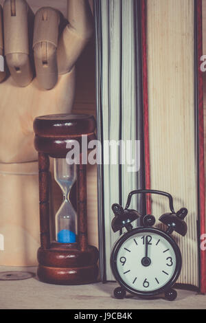 Orologio sveglia a clessidra con libro sulla scrivania in legno Foto Stock