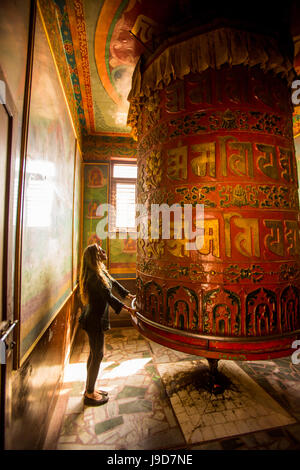 Donna orante presso la preghiera buddista ruota in Bouddha (Boudhanath) tempio, Sito Patrimonio Mondiale dell'UNESCO, Kathmandu, Nepal, Asia Foto Stock