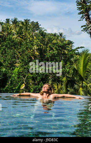 Donna godendo di un traboccare piscina al di sopra di una valle nel Kamandalu Resort Ubud, Ubud, Bali, Indonesia, Asia sud-orientale, Asia Foto Stock