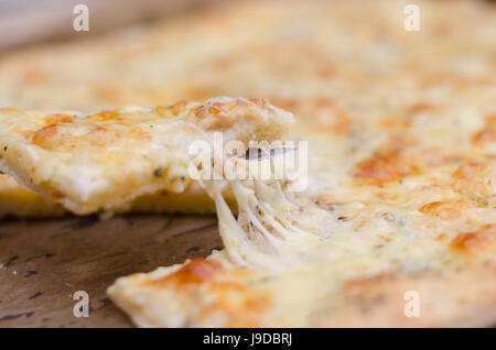 Serve una quattro formaggi pizza con formaggio fuso Foto Stock