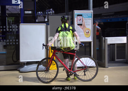 Ciclista a queen street stazione ferroviaria sotto il segno gaelico scotrail Foto Stock