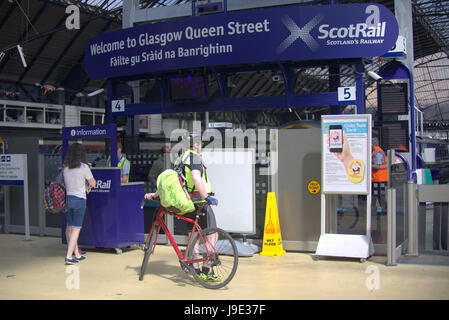 Ciclista a queen street stazione ferroviaria sotto il segno gaelico scotrail Foto Stock