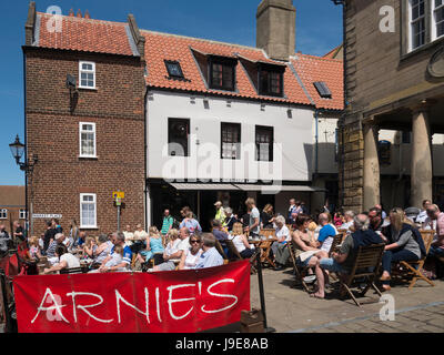 Turisti che si godono una sosta e ristoro presso i tavoli fuori Arnie's Bistro Café in luogo di mercato Whitby North Yorkshire, rinominato la Vecchia Griglia argento Foto Stock