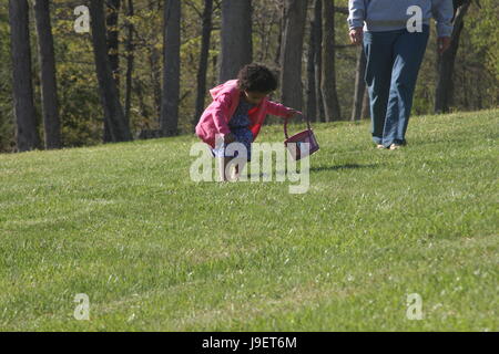 Bambina alla ricerca di uova di Pasqua in erba Foto Stock