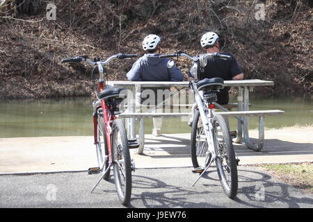 Due uomini adulti in appoggio sul banco dal fiume dopo la corsa in bicicletta Foto Stock