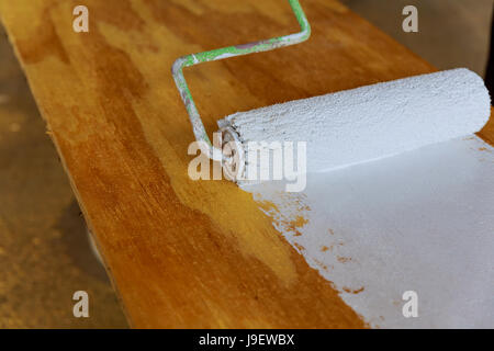 Verniciatura del legno con vernice bianca Casa di rullo di pittura,rullo di vernice Foto Stock