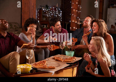 Giovani adulti con pizze a una festa a casa Foto Stock