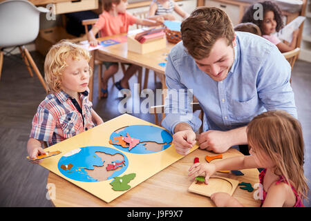 Insegnante e gli studenti usando le forme di legno nella Scuola Montessori Foto Stock