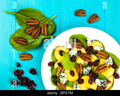 Pesche fresche e insalata di spinaci con noci pecan e formaggio blu contro uno sfondo blu Foto Stock