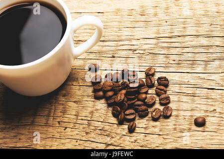 Tazza di caffè con i chicchi di caffè accanto ad essa - close up shot. Immagine filtrata: Croce trasformati effetto vintage. Foto Stock