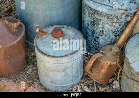 Vintage rusty lattine di olio di diverse dimensioni trascurate in un workshop di fattoria Foto Stock