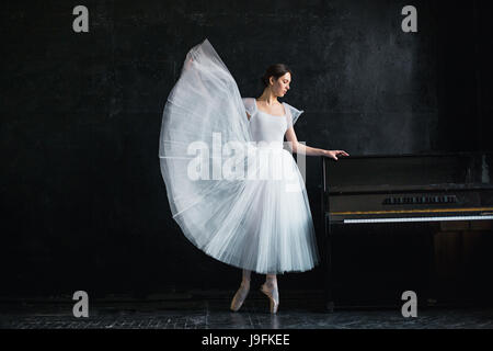 Giovane e incredibilmente bella ballerina è in posa di un nero studio Foto Stock