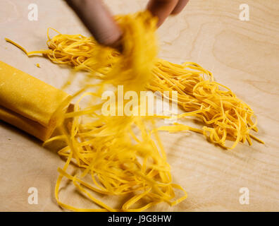 Tagliatelle. Tradizione artigianale italiana pasta fresca, a forma di  nastro. Il momento dopo il taglio nel procedimento di preparazione Foto  stock - Alamy