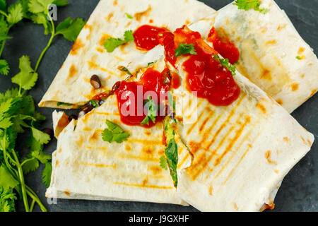 Burrito vegetariano si avvolge con fagioli, avocado e formaggio su una lavagna, vista dall'alto. Amore per un sano cibo vegan concept Foto Stock