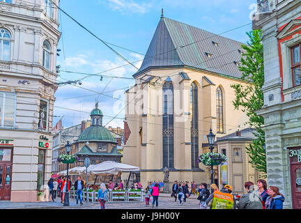 LEOPOLI, UCRAINA - 16 MAGGIO 2017: La vista dell'abside della cattedrale latina dalla piazza del mercato (Ploshcha Rynok), la cupola della Cappella Boim è visibile dietro il caffè Foto Stock