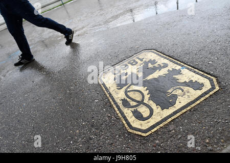 Monaco di Baviera, Germania. 02Giugno, 2017. dpatop - un uomo passa da un logo lion all'entrata del negozio della ventola sulla basi di formazione della Germania club di calcio TSV 1860 Monaco di Baviera durante la pioggia a Gruenewalder Straße a Monaco di Baviera, Germania, 02 giugno 2017. Dopo le attività sportive knock out durante la lotta per la seconda Bundesliga TSV 1860 di Monaco di Baviera ha a faccia la fine del calcio professionale al Gruenwalder Straße. Foto: Andreas Gebert/dpa/Alamy Live News Foto Stock