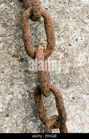 Spessore metallo arrugginito catena appesa sul muro di pietra Foto Stock