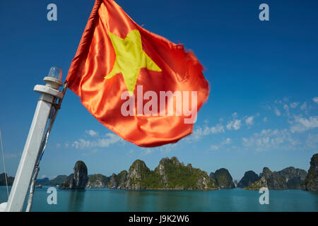 Bandiera vietnamita sulla barca turistica e pietre calcaree carsiche, la baia di Ha Long (UNESCO World Heritage Site ), Quang Ninh Provincia, Vietnam Foto Stock