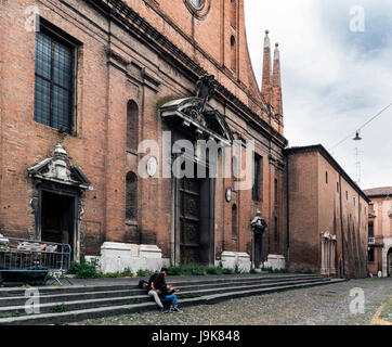 Ferrara, Emilia Romagna, Italia. Maggio 20, 2017. Giovane seduto sui gradini della chiesa di San Paolo, nella piazza di Alberto Schiatti Foto Stock