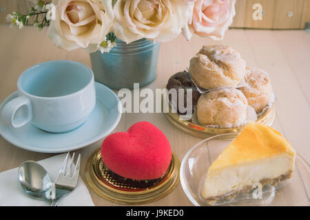 Vaso di bouquet di rose nel secchio in alluminio con mirtilli cheesecake e il profumo di rosa tea con miele, tea break, sul tavolo di legno, set di bellissimi fiori Foto Stock