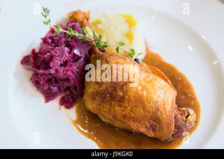 Confit di anatra con cavolo viola e purea di patate su piastra bianca Foto Stock