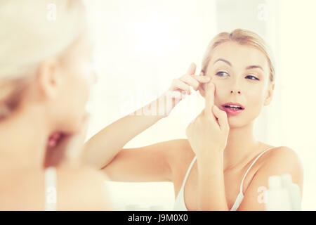 La donna la spremitura brufolo a Specchio bagno Foto Stock