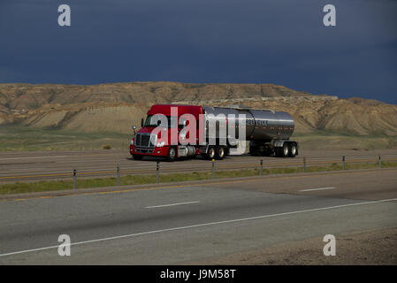 Un Rosso Freightliner Semi-Truck tira un "d'Argento" Groendyke cisterna rimorchio verso il basso un rurale noi Interstate. Foto Stock