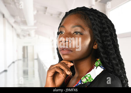 Ritratto di bella African American imprenditrice con la mano sul mento all'interno di edificio per uffici Foto Stock