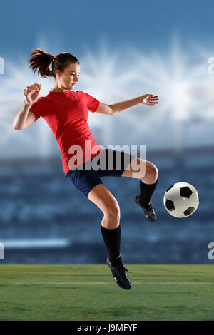 Ritratto di donna giocatore di calcio calci palla all'interno stadium Foto Stock