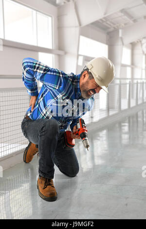 Lavoratore ispanica sofferenza lesioni alla schiena all'interno di edificio Foto Stock