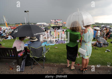 Racegoers riparo sotto gli ombrelloni sul Signore giorno durante il 2017 Investec Epsom Derby Festival presso la Epsom Racecourse, Epsom. Foto Stock