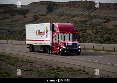 Un Rosso Freightliner Semi-Truck tira un bianco 'C.R. Inghilterra " rimorchio lungo un rurale noi Interstate. Foto Stock