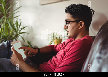 Uomo con tavoletta digitale comodamente seduti sul divano di casa Foto Stock